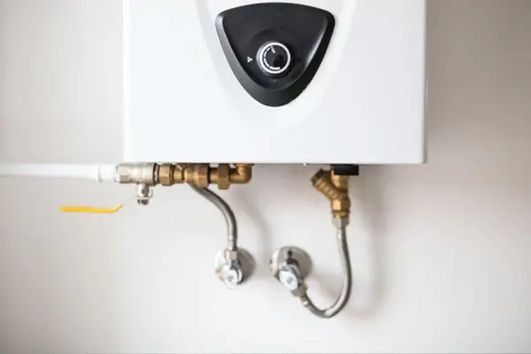 Plumbing connections to a tankless water heater. Knowing the pros and cons of tankless heaters is an important consideration when purchasing.