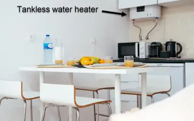 Kitchen with a table and food on it and a tankless water heater on the wall partially concealed by a cabinet.