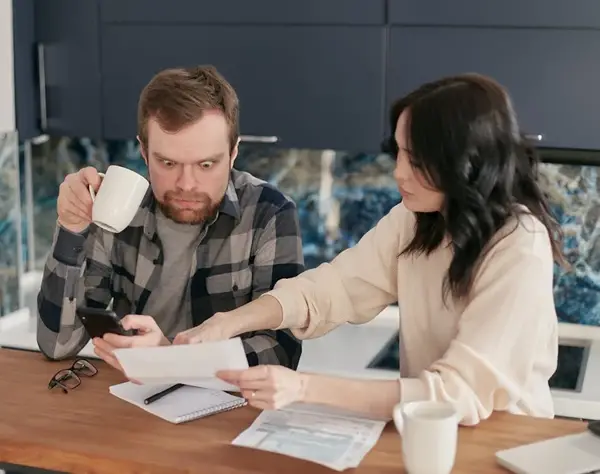 Husband shocked as his wife points at the water utility bill.