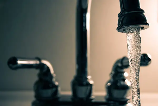 Water pouring out of a stainless-steel faucet.